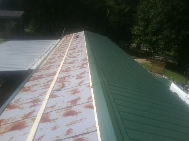 Old rusted panels beside newly installed green metal roofing — Wind Damage Roof Repair by Roofing Brothers in Moundridge