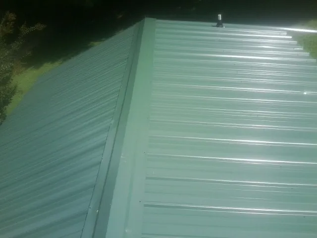 New green metal panels meeting at the ridge of a roof — Flat Roof Repair work by our crew in Moundridge