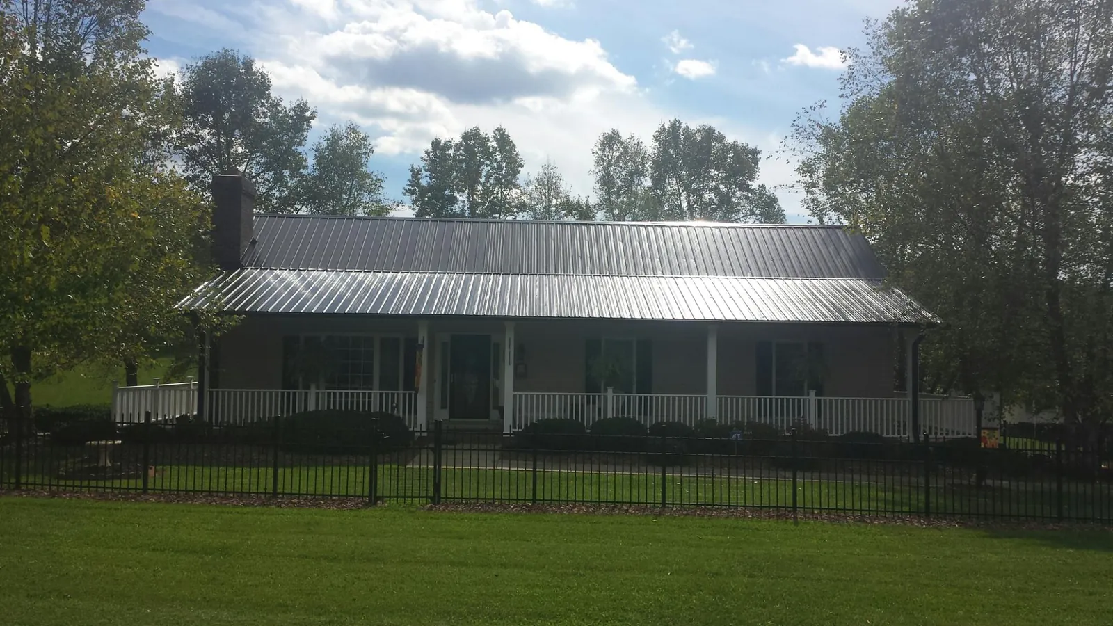 Gray metal roof on a brick ranch with a full width front porch — Gutter Guard Installation work by our crew in Moundridge