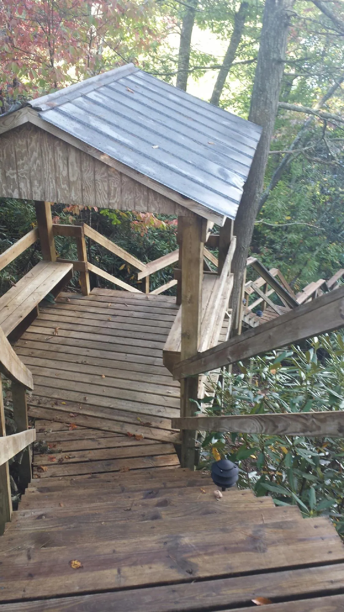 Metal roofed shelter over wooden steps on a wooded walkway — Skylight Repair & Installation work by our crew in Moundridge