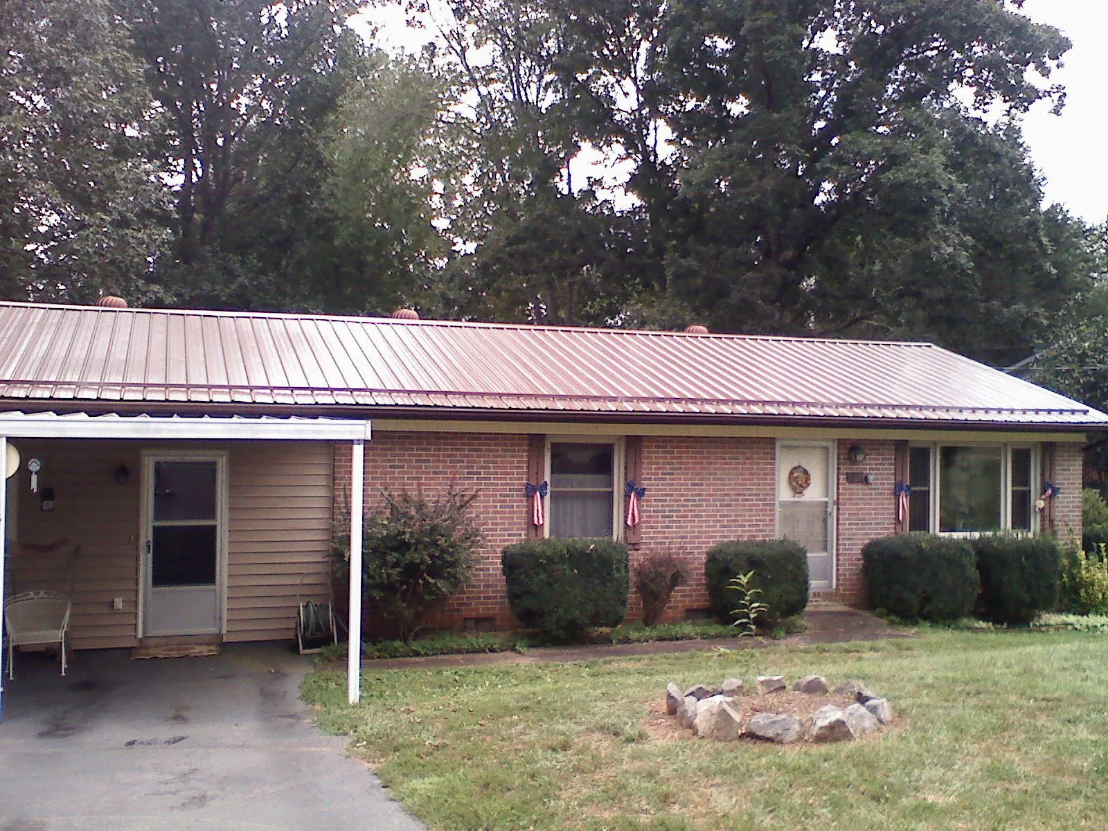 Bronze metal roof and carport on a brick ranch home — Roof Repair work by our crew in Moundridge