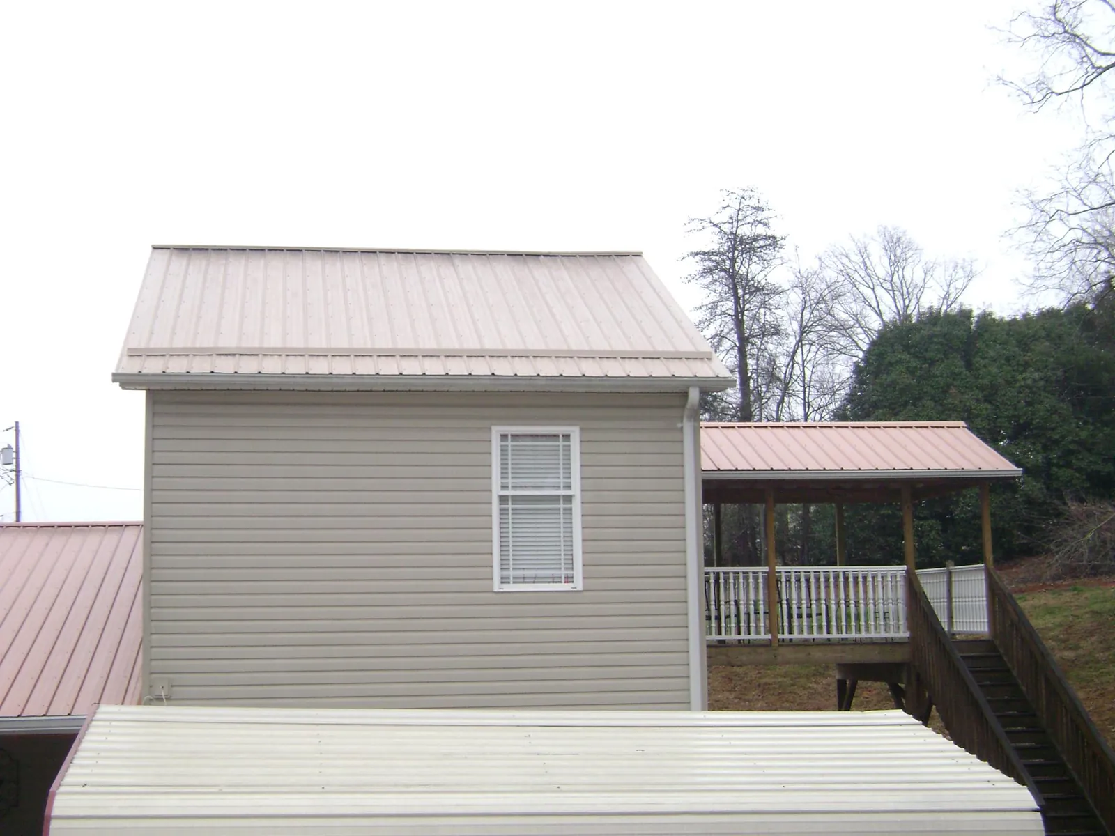 Tan metal roofs on a two story addition and attached porch, from a Roof Replacement job in Moundridge