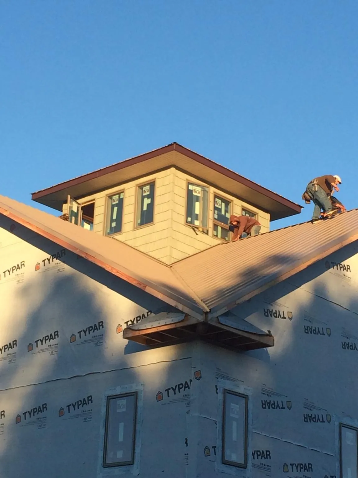 Roofers working around a rooftop cupola on a new metal roof at sunset — Roof Waterproofing in Moundridge by Roofing Brothers